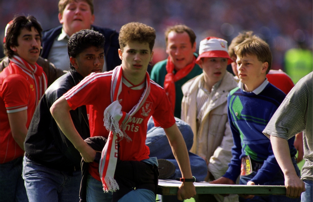 FILE PHOTO: Fans carry an injured man from the pitch  / ACTION IMAGES