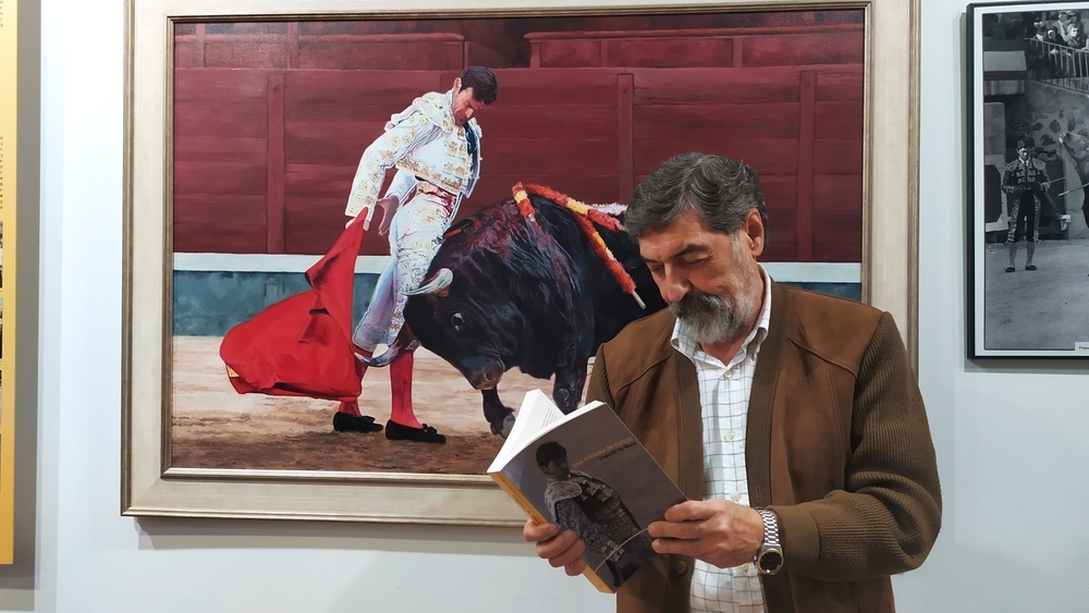 Victorino Zapatero, autor del libro, hojea la obra delante de un cuadro de Eugenio de Mora que preside el Aula Cultural Domingo Ortega.