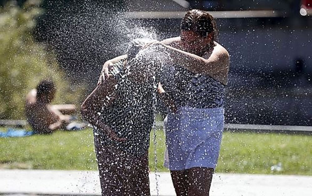 Dos señoras se refrescan en un parque de Madrid en uno de los veranos más calurosos de la capital.
