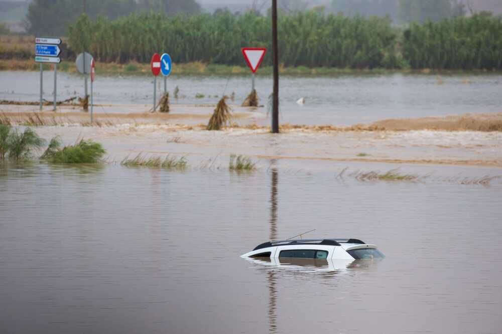 Uno de los coches tapados por el agua acumulada en la zona.